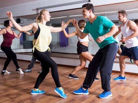 Young smiling men and women dancing swing in dance hall